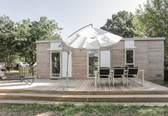 Holz-Lodge mit Terrasse, Sonnenschirm und Gartenmöbeln bei Flower Camping L'Ile d'Offard, Frankreich.