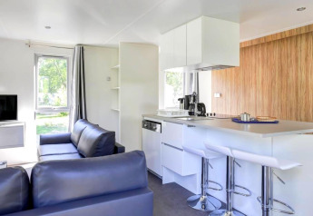 Salón y cocina modernos en Stacaravan Premium de Flower Camping L'Ile d'Offard en Francia, con decoración luminosa.