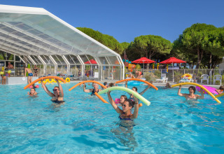 Holidaymakers enjoy a water aerobics class with pool noodles at Flower Camping Le Bois d'Amour in Brittany, France.