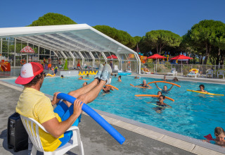 Instructor leads aqua aerobics class with pool noodles at Flower Camping Le Bois d'Amour in Brittany, France.
