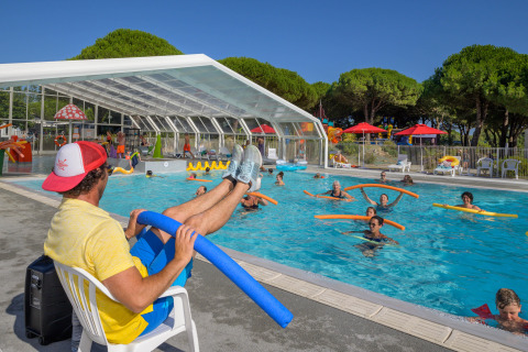 Schwimmlehrer gibt Poolkurs mit Schwimmnudeln im Flower Camping Le Bois d’Amour in der Bretagne, Frankreich.