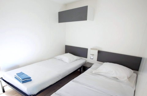 Zwei Einzelbetten in einem hellen Zimmer im Stacaravan Premium bei Flower Camping L'Ile d'Offard, Frankreich.