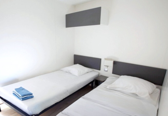 Zwei Einzelbetten in einem hellen Zimmer im Stacaravan Premium bei Flower Camping L'Ile d'Offard, Frankreich.