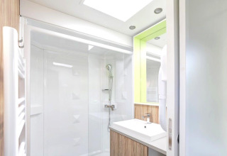 Modern bathroom with shower, mirror, and sink in Stacaravan Premium at Flower Camping L'Ile d'Offard, France.