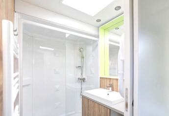 Modern bathroom with shower, mirror, and sink in Stacaravan Premium at Flower Camping L'Ile d'Offard, France.