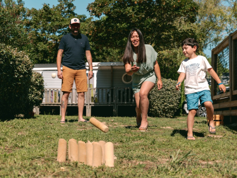 Familia jugando un juego de lanzamiento al aire libre en Flower Camping Le Bois d'Amour en Bretaña, Francia.
