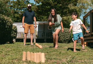 Familie spielt gemeinsam ein Wurfspiel im Freien im Flower Camping Le Bois d'Amour in der Bretagne, Frankreich.