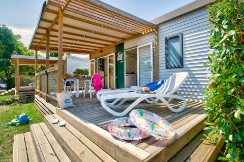 Zonnig terras bij chalet met ligzetel, opblaasbanden, kinderspeelgoed en gezellige zithoek buiten.