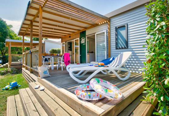 Zonnig terras van lodge met ligstoel, zwembanden, kinderspeelgoed en uitnodigend buiteneethoekje.