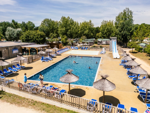 Outdoor swimming pool with sun loungers and parasols at Camping Demoiselles Plage, Pays de la Loire, France.
