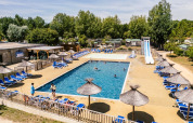 Buitenzwembad met ligstoelen en rieten parasols op Camping Demoiselles Plage in Pays de la Loire, Frankrijk.