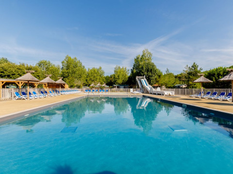 Outdoor swimming pool with loungers and water slide at Camping Demoiselles Plage, Pays de la Loire, France.