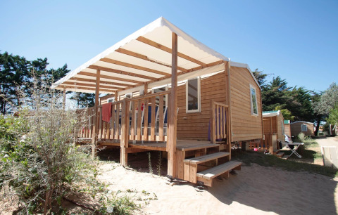 Wooden cabin with covered porch at Camping Demoiselles Plage holiday park, Pays de la Loire, France.