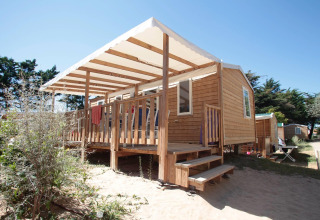 Wooden cabin with covered porch at Camping Demoiselles Plage holiday park, Pays de la Loire, France.