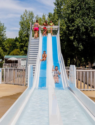 Children playing on a waterslide at Camping Demoiselles Plage, Pays de la Loire, France.