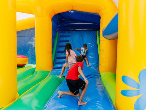 Children play on a colorful bouncy castle at Camping Demoiselles Plage holiday park in Pays de la Loire, France.