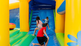 Children play on a colorful bouncy castle at Camping Demoiselles Plage holiday park in Pays de la Loire, France.
