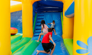 Children play on a colorful bouncy castle at Camping Demoiselles Plage holiday park in Pays de la Loire, France.