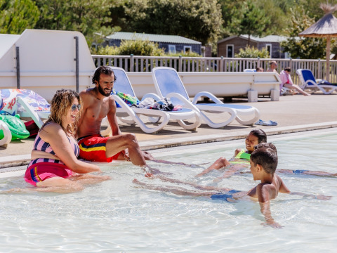 Family having fun together in the swimming pool at Camping Demoiselles Plage holiday park, Pays de la Loire, France.