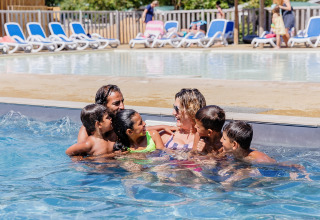 Gezin geniet samen van het zwembad bij Camping Demoiselles Plage, een vakantiepark in Pays de la Loire, Frankrijk.