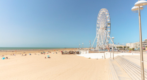 Spiaggia sabbiosa con visitatori sparsi e una grande ruota panoramica vicino a Saint-Hilaire-de-Riez, Pays de la Loire.
