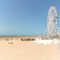 Playa de arena con visitantes dispersos y una gran noria cerca de Saint-Hilaire-de-Riez, Pays de la Loire.
