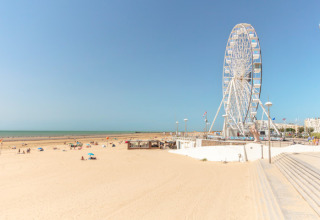 Playa de arena con visitantes dispersos y una gran noria cerca de Saint-Hilaire-de-Riez, Pays de la Loire.