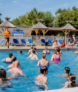 Guests participate in water aerobics in the pool at Camping Demoiselles Plage in Pays de la Loire, France.