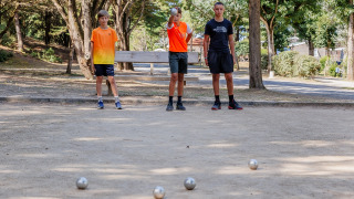 Drie jongeren spelen petanque op een zandterrein bij Camping Demoiselles Plage, Pays de la Loire, Frankrijk.