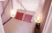 Imagen de una cama acogedora con cojines rojos y lámparas de noche en una tienda de safari.