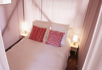 Imagen de una cama acogedora con cojines rojos y lámparas de noche en una tienda de safari.