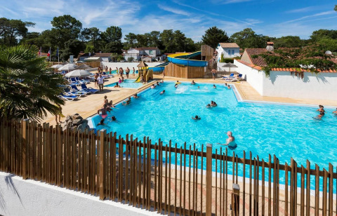 Familias disfrutan de la piscina y el tobogán acuático en Flower Camping Les Dunes en Pays de la Loire, Francia.