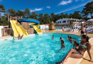 Vakantiegangers genieten van glijbanen en het zwembad bij Flower Camping Les Dunes in Pays de la Loire, Frankrijk.