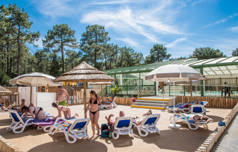 Gäste entspannen sich auf Liegestühlen am Pool im Ferienpark Flower Camping Les Dunes in Pays de la Loire.