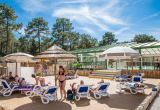 Ferieparkets udendørs poolområde på Flower Camping Les Dunes, med gæster der solbader og bader i solskin.