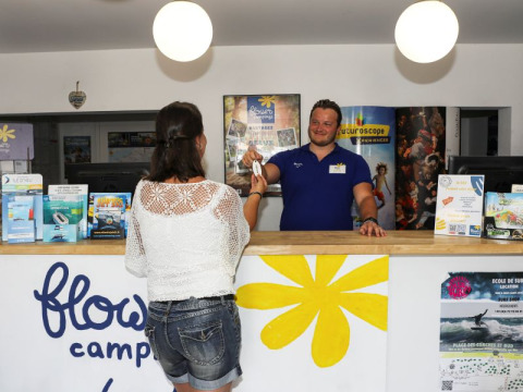 Mujer registrándose en la recepción de Flower Camping Les Dunes en Pays de la Loire, Francia, parque vacacional.