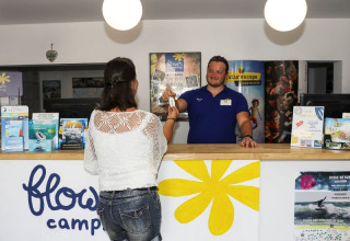 Vrouw checkt in bij de Flower Camping Les Dunes receptie, vakantiepark in Pays de la Loire, Frankrijk.