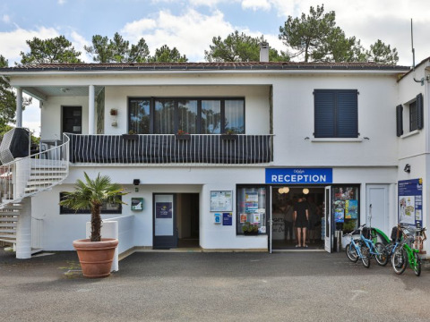 Receptionen ved Flower Camping Les Dunes feriepark i Pays de la Loire, Frankrig, med cykler og grønne omgivelser.