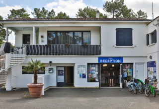 Receptionen ved Flower Camping Les Dunes feriepark i Pays de la Loire, Frankrig, med cykler og grønne omgivelser.