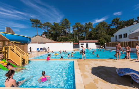 Buitenzwembad met glijbaan en gezinnen op Flower Camping Les Dunes, Pays de la Loire, Frankrijk.