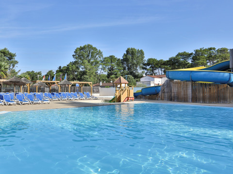 Outdoor pool with water slide, sun loungers, and parasols at Flower Camping Les Dunes, Pays de la Loire, France.
