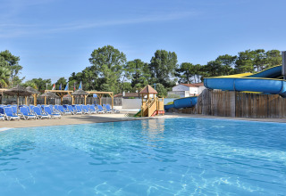 Outdoor pool with water slide, sun loungers, and parasols at Flower Camping Les Dunes, Pays de la Loire, France.