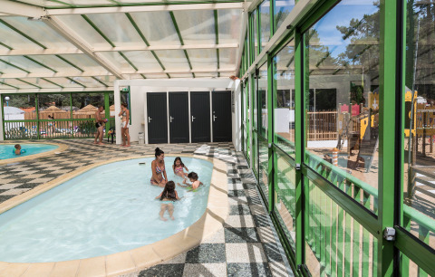Indoor pool area at Flower Camping Les Dunes in Pays de la Loire, France, featuring children playing.