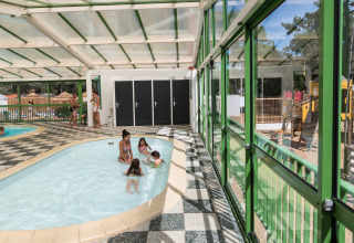 Zona de piscina cubierta en Flower Camping Les Dunes, Pays de la Loire, Francia, con niños jugando.