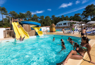 Familien vergnügen sich im Pool mit Wasserrutsche im Flower Camping Les Dunes, Pays de la Loire, Frankreich.