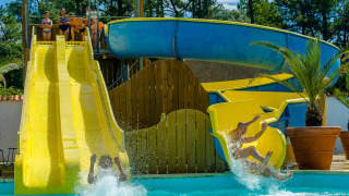 Børn og voksne nyder farverige vandrutsjebaner ved Flower Camping Les Dunes, Pays de la Loire, Frankrig.