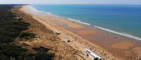 Vista aérea de la playa y el mar cerca de Flower Camping Les Dunes en Pays de la Loire, Francia, con visitantes.