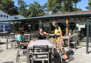 Outdoor dining area at Flower Camping Les Dunes, Pays de la Loire, France, with guests being served.