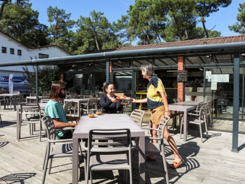Udendørs restaurantområde på Flower Camping Les Dunes i Pays de la Loire med gæster og servering.