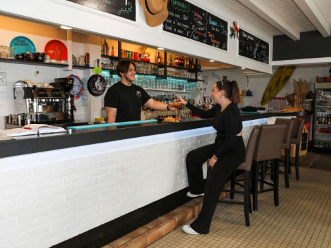 Una cliente riceve una bevanda dal barista al Flower Camping Les Dunes a Pays de la Loire, Francia.